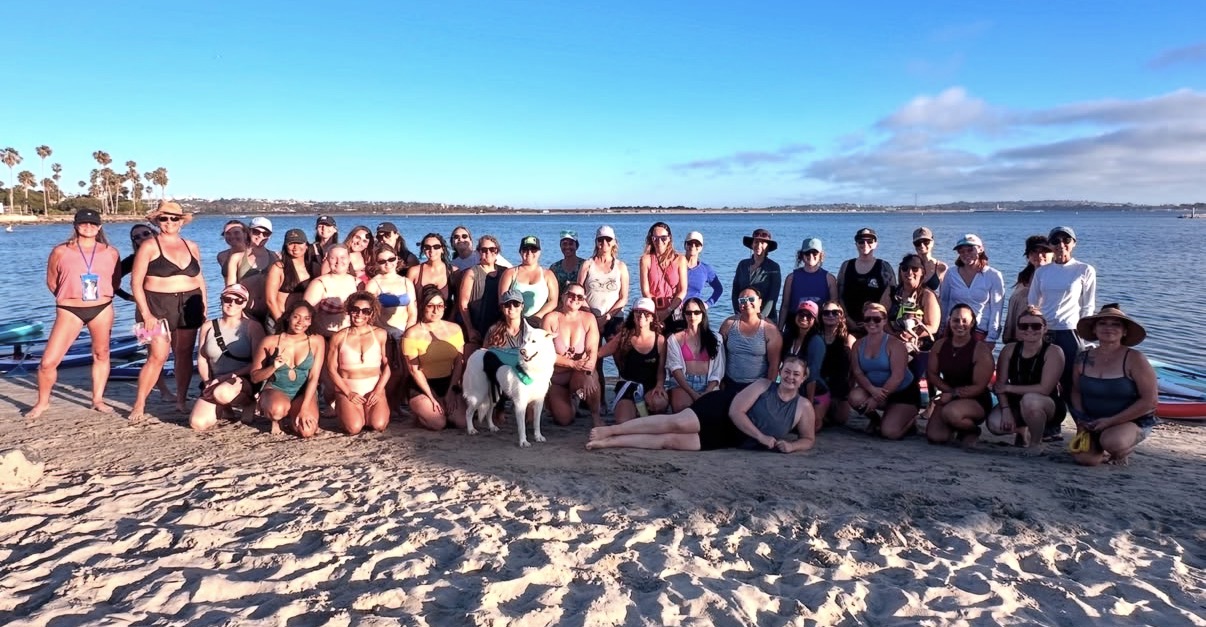 The Girls Who Paddle SD community gathered on the beach at Mission Bay after a paddle